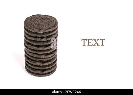 Chocolate black thin cookie with white filling, delicious milk sweet cookie scattered on a white background. Stock Photo