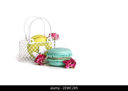 Blue and yellow macarons on a white isolated background. Metal decorative small basket with handles