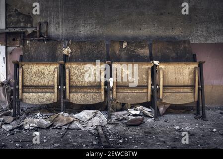 Old damaged theater seats in an abandoned ruined room Stock Photo