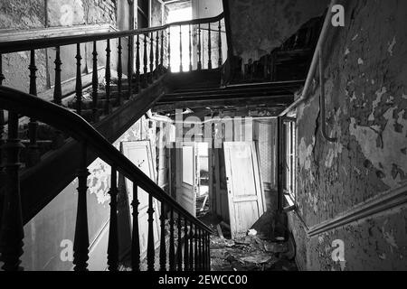 A grayscale shot of a staircase in an abandoned building Stock Photo