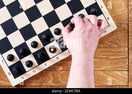 Mans hand take a black pawn to do a first chess move. Leisure activity and games Stock Photo