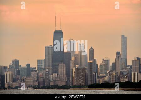 Chicago, Illinois, USA. A muted sunrise casts light into the clouds above a portion of the Chicago skyline and Lake Michigan. Stock Photo