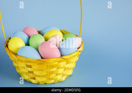 Easter eggs in basket with copy space on blue background. Easter composition. Stock Photo