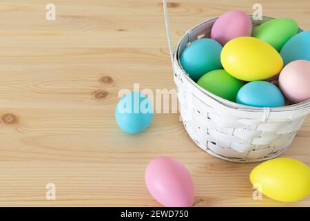 Easter colored eggs in the basket on wooden table background Stock Photo