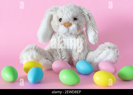 Easter stuffed bunny with colored eggs on pink background Stock Photo
