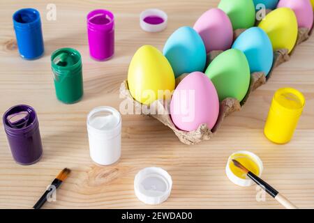 Easter eggs and colored paints with paintbrushes on the table. Easter craft concept. Stock Photo