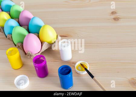 Easter eggs and colored paints with paintbrushes on the table. Easter craft concept. Stock Photo