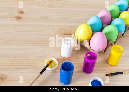 Easter eggs and colored paints with paintbrushes on the table. Easter craft concept. Stock Photo