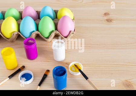 Easter eggs and colored paints with paintbrushes on the table. Easter craft concept. Stock Photo