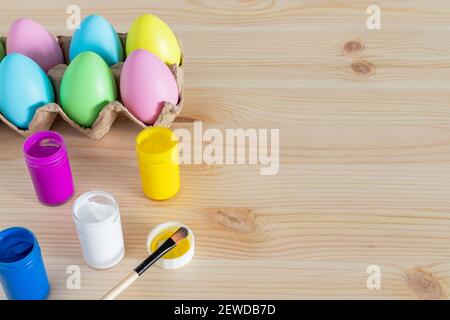 Easter eggs and colored paints with paintbrushes on the table. Easter craft concept. Stock Photo