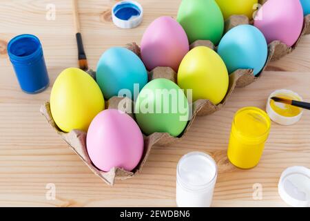 Easter eggs and colored paints with paintbrushes on the table. Easter craft concept. Stock Photo