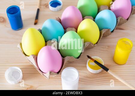 Easter eggs and colored paints with paintbrushes on the table. Easter craft concept. Stock Photo
