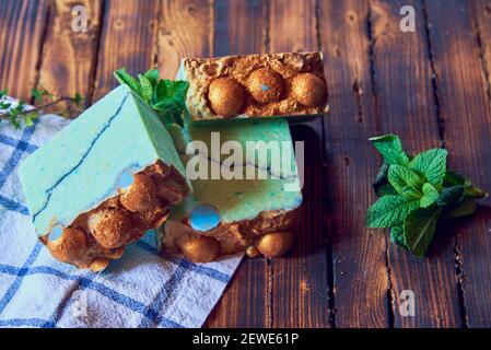 A fragrant green organic handmade soap decorated with mint leaves and a kitchen towel on a brown wooden countertop. Stock Photo