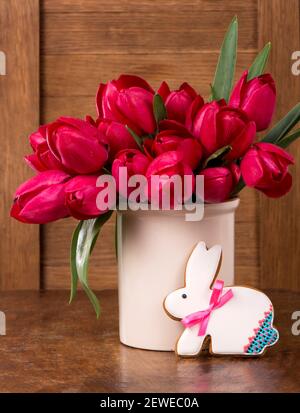 Pink tulips and easter bunny cookie on wooden background. Spring or easter concept Stock Photo