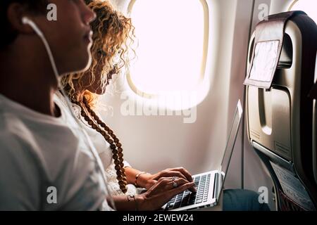 People couple use laptop computer on board in airplane flight with internet wireless connection service - concept of modern worker and travel smart wo Stock Photo
