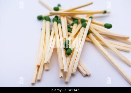 Small pile of wooden matches with green heads on a white background. Selective focus. Stock Photo
