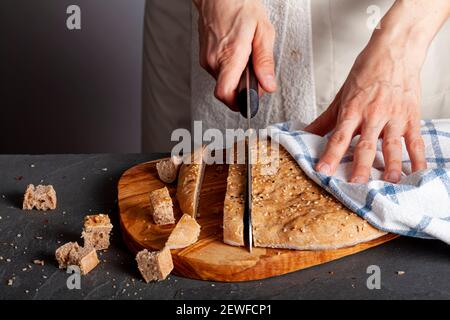 A woman chef is slicing fresh baked homemade Turkish Flat bread known as pide or pita on wooden chopping board. The wholegrain pita bread is round wit Stock Photo