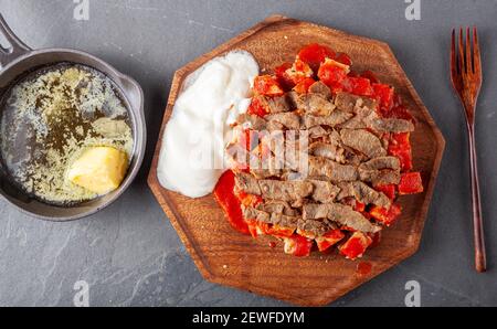 Traditional Turkish doner kebab (shawarma) made with charcoal grilled sliced lamb meat served on diced Turkish flat bread pide with tomato sauce. A ca Stock Photo