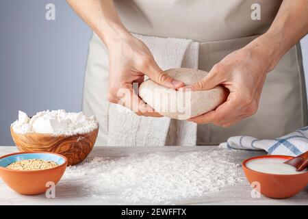 Preparation of homemadeTurkish flat bread, pide or pizza base in the kitchen. A woman chef is kneading  and flattening the whole grain organic dough i Stock Photo