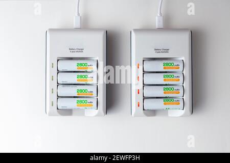 flat lay image of two rechargeable battery chargers powered through USB cables. Each has a stack of 4 AA rechargeable batteries with 2800 mAh capacity Stock Photo