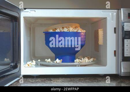 Homemade fat and salt free popcorns in a silicon BPA free collapsible popcorn popper bowl inside microwave. This bowl offers guilt free instant popcor Stock Photo
