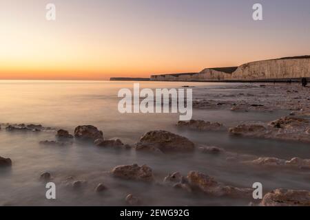 Full snow February moon setting over the east Sussex coast at low tide in south east England from Birling Gap Seven Sisters Stock Photo