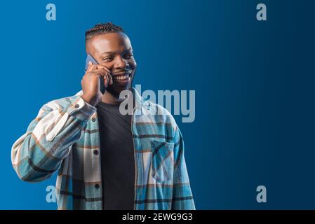 Handsome black man talking on the mobile happy and smiling. Mid shot. Blue background. Stock Photo