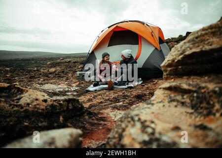 Caucasian romantic couple enjoying camping in mountain sitting under tent Stock Photo