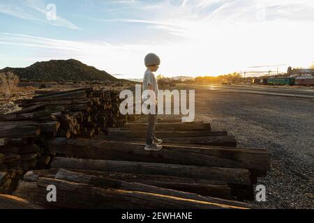 7 year old boy standing alone on railroad ties at sunset Stock Photo