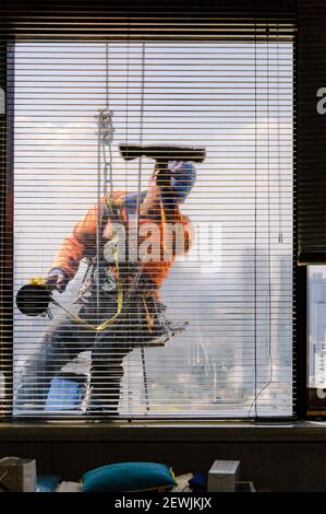 Bangkok, Thailand – December 1, 2015: A daring profession. A window cleaner hanging on his safety ropes, cleaning the windows of a high-rise building. Stock Photo