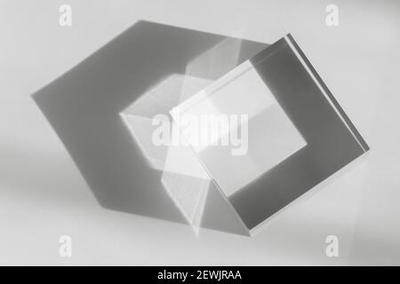 Glass transparent cube with sun reflection, light and shadow on white background. Physics refraction effect, translucent prism. Decor for flat lay Stock Photo