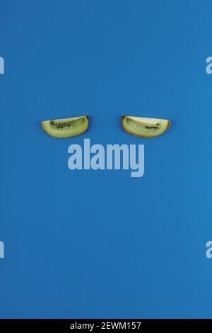 Kiwi slices like eyes on a blue background. Food concept for sleep and insomnia treatment Stock Photo