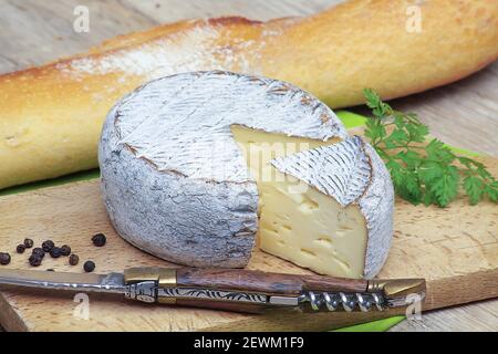 Tomme de Savoie cheese on a cutting board Stock Photo