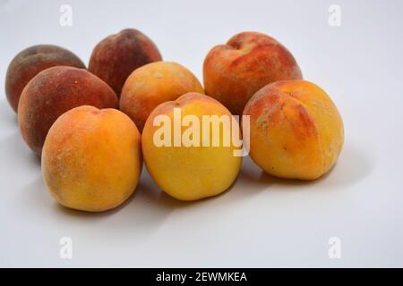 Tasty and useful fresh fruits, ripe red and orange peaches with a terry white skurt are located on a white background. Stock Photo