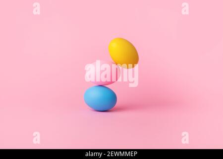 three colorful easter eggs balancing over pink background, balance concept Stock Photo