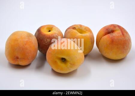 Tasty and useful fresh fruits, ripe red and orange peaches with a terry white skurt are located on a white background. Stock Photo