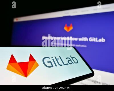 Smartphone with business logo of American DevOps platform GitLab Inc. on screen in front of company website. Focus on center-left of phone display. Stock Photo