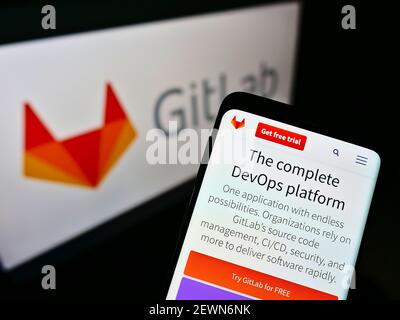 Mobile phone with company website of American DevOps platform GitLab Inc. on screen in front of business logo. Focus on center of cellphone display. Stock Photo