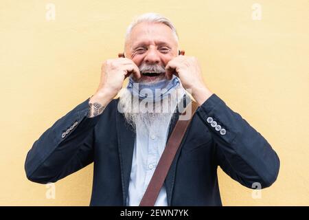 Portrait of happy hipster senior man with mask under chin - Focus on face Stock Photo