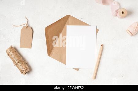 Blank white card with craft paper envelope in hands Stock Photo