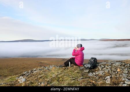 Teesdale, County Durham, UK. 3rd March 2021. UK Weather.  A woman enjoys a spectacular view above the clouds as a temperature inversion creates thick fog at lower levels in Northeast England. Credit: David Forster/Alamy Live News Stock Photo