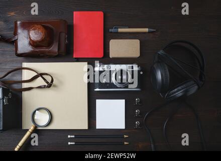 Vintage travel items. Photo of blank stationery and retro camera on wooden background. Flat lay. Stock Photo