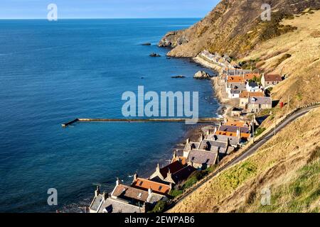 CROVIE VILLAGE ABERDEENSHIRE SCOTLAND A ROW OF HOUSES JETTY WALL AND BLUE GREEN SEA  OF THE BAY Stock Photo