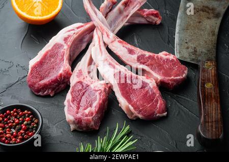 Raw fresh lamb loin chops set, with ingredients carrot orange, herbs, on black stone background Stock Photo