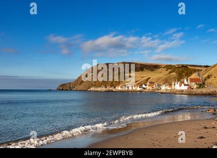 CROVIE VILLAGE ABERDEENSHIRE SCOTLAND A ROW OF HOUSES WITH RED ROOF TILES AND WAVES OVER A SMALL SANDY BEACH