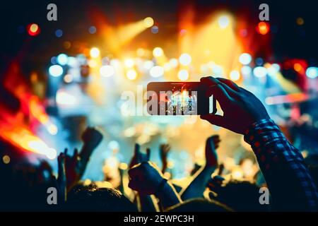 Man takes a picture of the show at the concert hall using a smartphone. Stock Photo