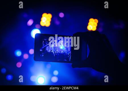 Man takes a picture of the show at the concert hall using a smartphone. Stock Photo