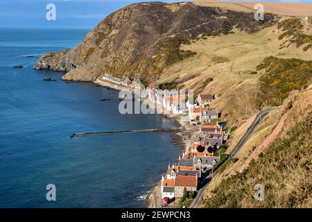 CROVIE VILLAGE ABERDEENSHIRE SCOTLAND THE HEADLAND ROW OF HOUSES THE JETTY WALL AND BLUE SEA  AND SKY Stock Photo