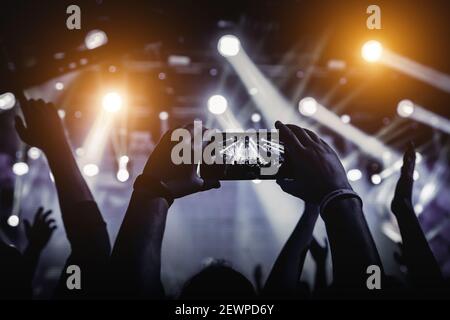 Man takes a picture of the show at the concert hall using a smartphone. Stock Photo