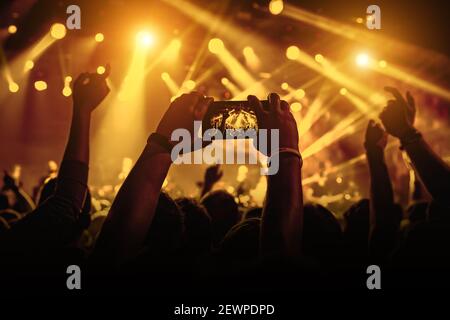 Man takes a picture of the show at the concert hall using a smartphone. Stock Photo